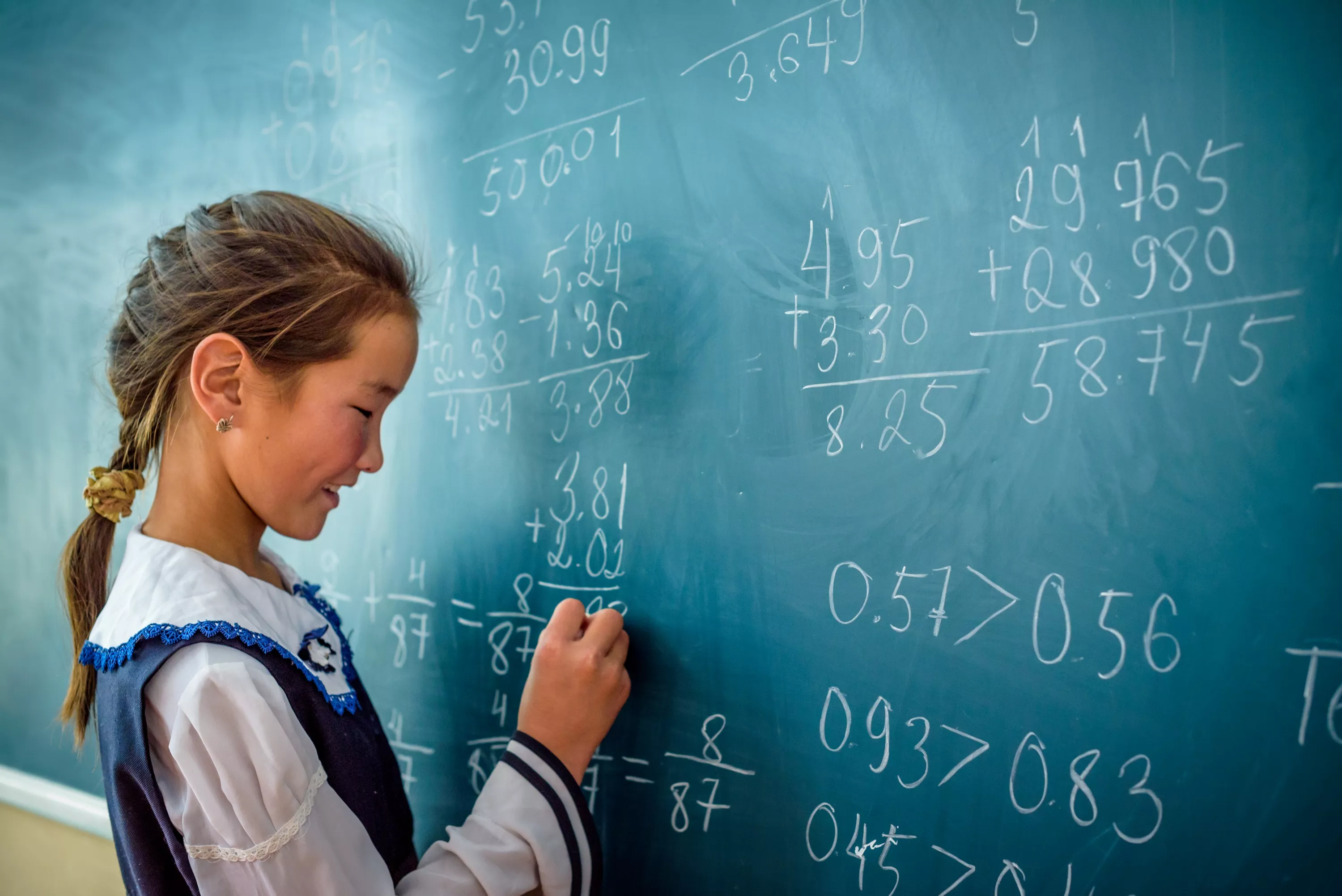 A little girl is writing on the blackboard