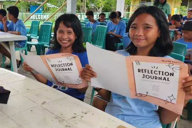 children holding out the reflection journal in Antique Philippines