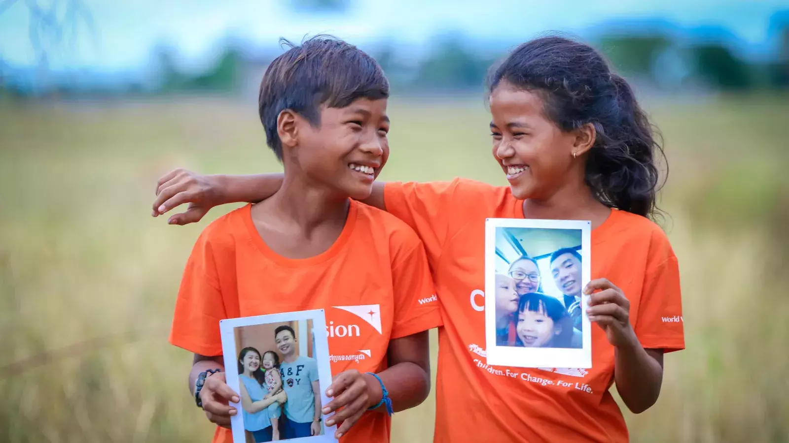 Children holding up photo of sponsors