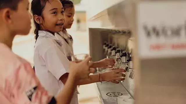 Children filling cups at outdoor water station