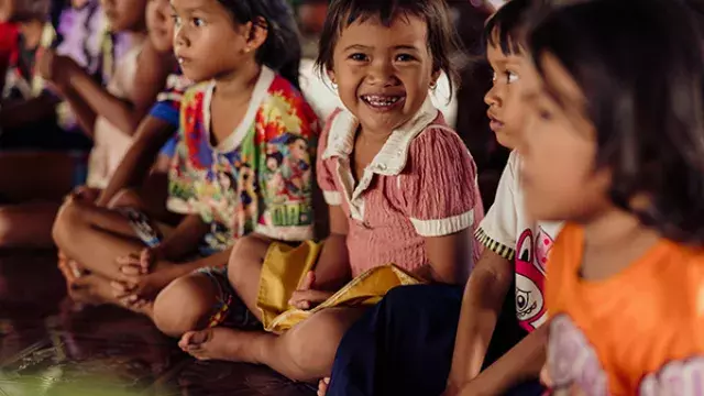 Children sitting closely together indoors smiling