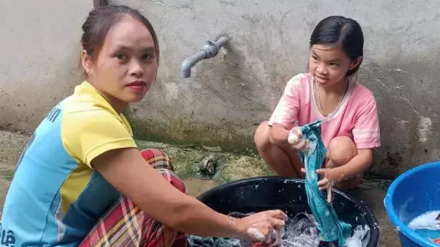 Two people hand‑washing clothes outdoors