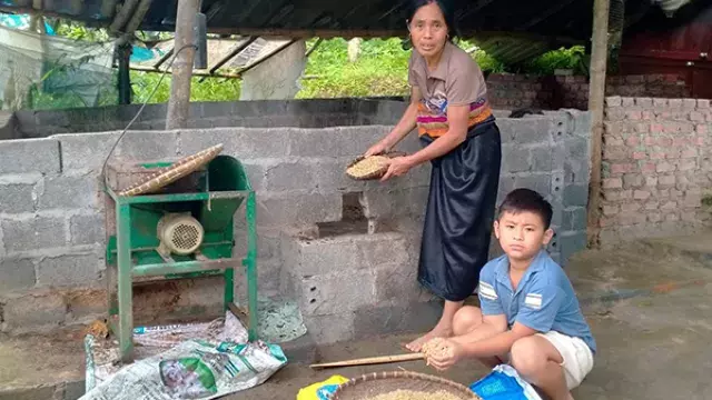 Adult and child milling grain outdoors
