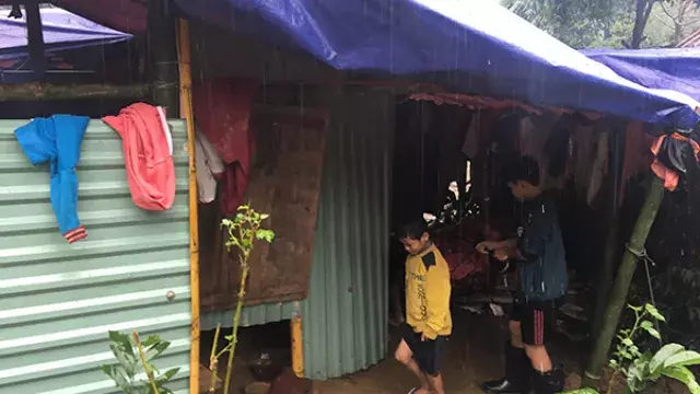 Children near small shelter with tarp roof in rain
