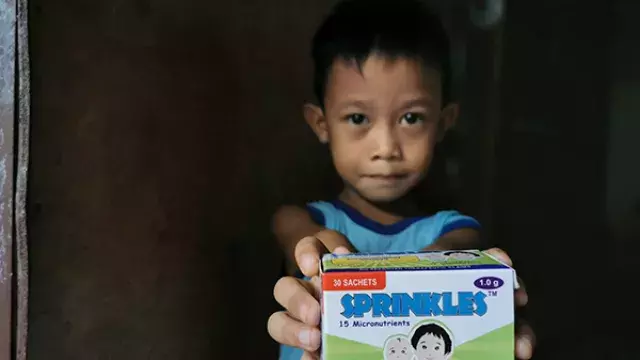 Child holding box of micronutrient supplement sachets