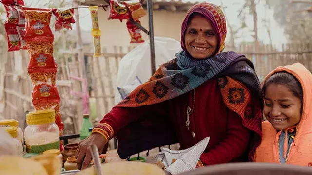 Two people at rural food stall with pots and snacks