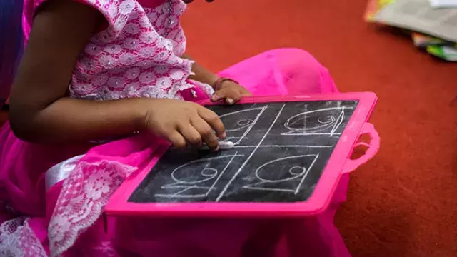 Child drawing on chalkboard with outlined shapes
