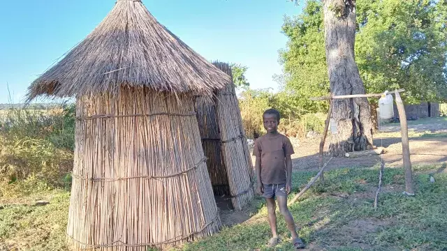  Boy from Sioma Zambia standing next to the newly built toilet in his home 