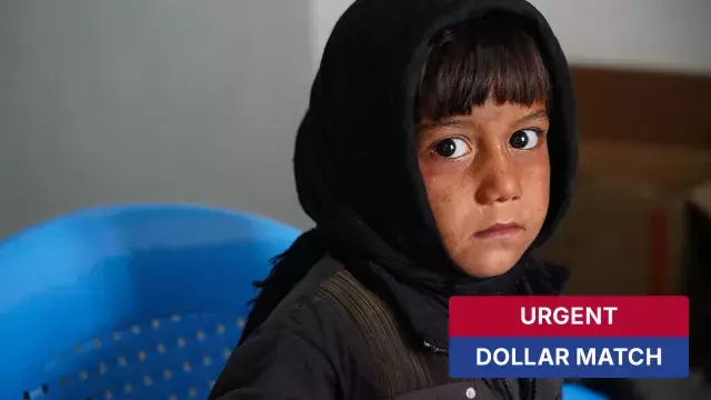 Child in headscarf sitting on blue chair with urgent dollar match label