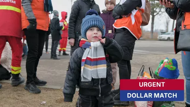 Child in winter clothes near volunteers with urgent sign